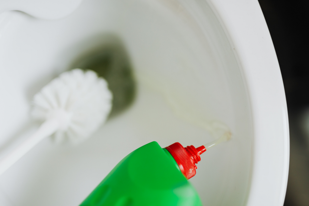 Green toilet bowl liquid cleaner and white scrub down a toilet bowl