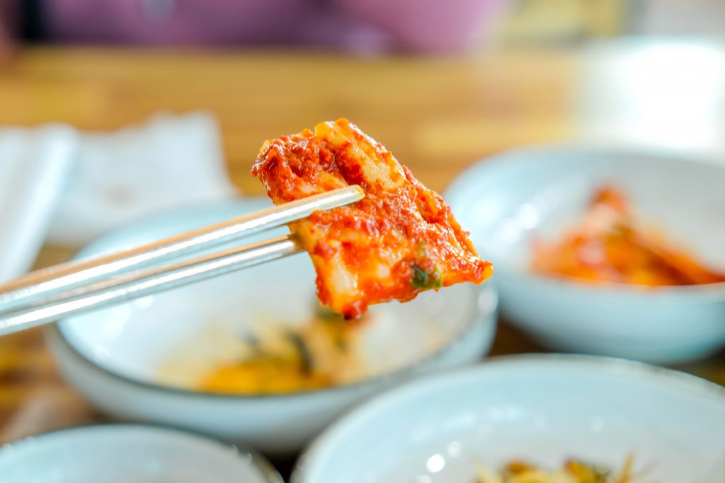Unrecognized people eating kimchi as appetizer during lunch
