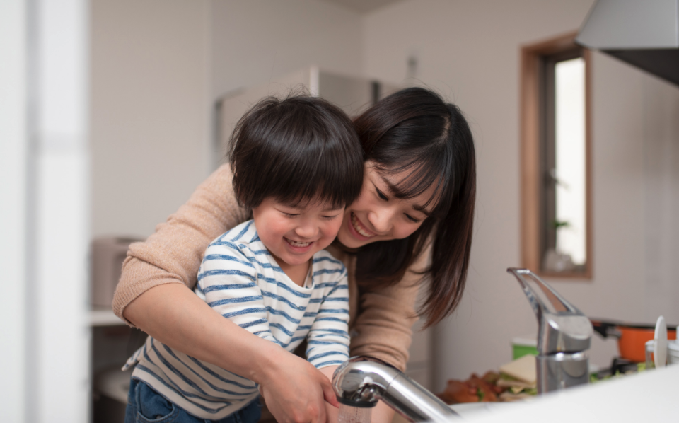 Asian woman washing hands with a young boy