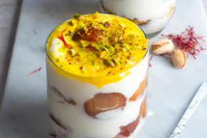 indian dessert parfait layered with gulab jamun and yoghurt, and topped with saffron milk mixture, chopped pistachios and saffron.