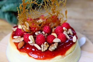 christmas cheesecake topped with strawberry jam, candy, mixed nuts and sliced raspberries and strawberries