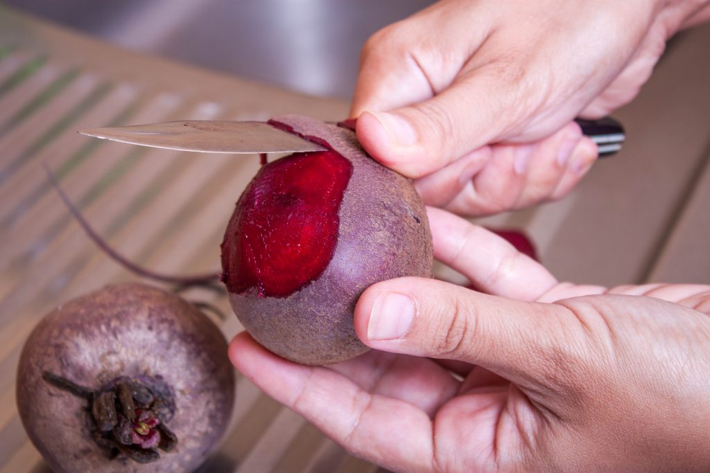 Female hands clean the beetroot with a knife