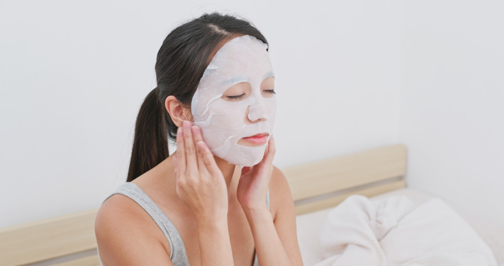 Woman,Apply,Facial,Paper,Mask,On,Face,At,Home