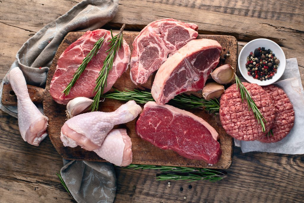 Different types of raw meat on a dark brown wooden background