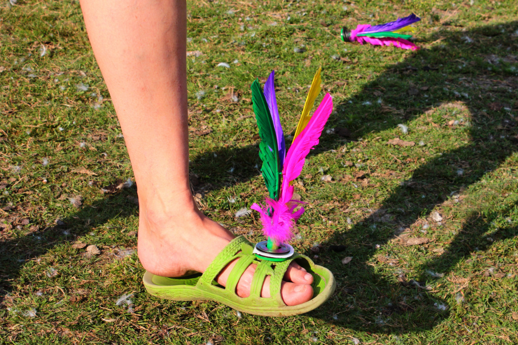 Chapteh A person's foot balancing a colourful feathered shuttlecock