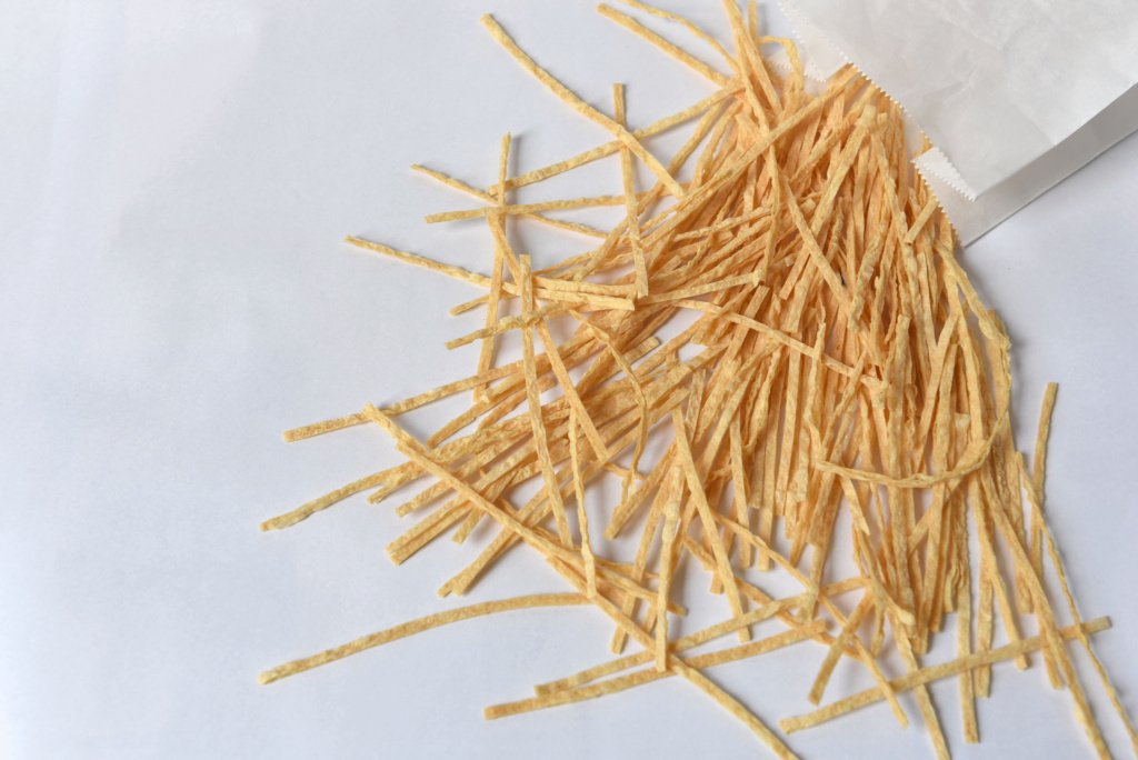 Dried Fish Fillet Snack Long strips of dried fish fillet snack arranged artfully on a light-coloured background