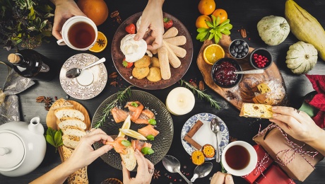 Top view of a table laden with food for Christmas, and hands sharing food over the table